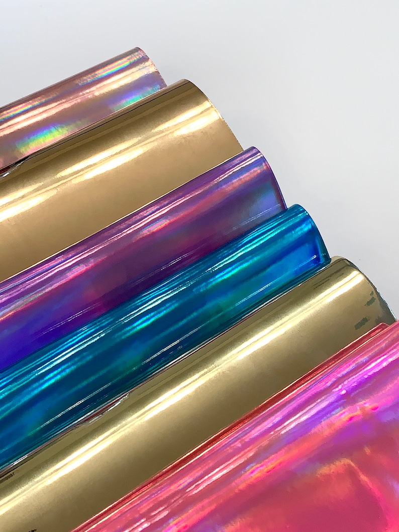 Op de afbeelding: Een stapel van zes iriserende vinylvellen in verschillende kleuren, waaronder goud, paars, blauw en roze.