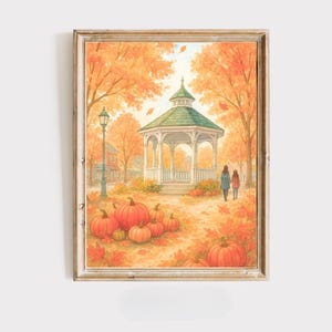 May include: A framed watercolour print of an autumnal scene. The artwork shows a gazebo with a green roof, surrounded by orange trees and pumpkins. Two figures walk along a path. The overall theme is autumn and harvest.