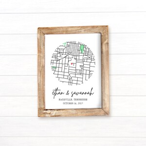 May include: A framed print featuring a map of Nashville, Tennessee, with a highlighted area. The print includes the names "Ethan & Savannah" and the date "October 16, 2017." The frame is made of light brown wood.