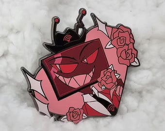 May include: A red and black enamel pin featuring a cartoon character with a square head, a mischievous grin, and a red antenna. The character is wearing a black hat with a red antenna and is surrounded by pink roses.