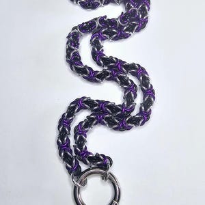 May include: A black and purple chain necklace with a silver ring clasp.
