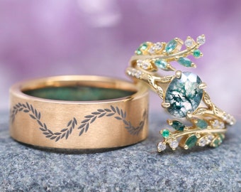May include: A pair of gold wedding bands with a leafy design. The band on the left has a delicate, engraved pattern of leaves. The band on the right features a large, oval-shaped green moss agate gemstone surrounded by a leafy design with small green gemstones.
