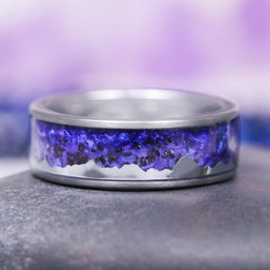 May include: A silver ring with a purple and black mountain range design. The ring is made of titanium and has a polished finish.