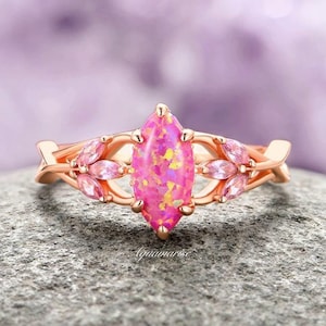 May include: A rose gold ring with a pink opal marquise-shaped gemstone surrounded by smaller pink gemstones in a leaf design.