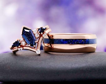 May include: A rose gold ring set featuring a marquise-cut blue sandstone centre stone, smaller blue sandstone accents, and clear round stones, paired with a rose gold band containing a central inlay of sparkling blue sandstone material.