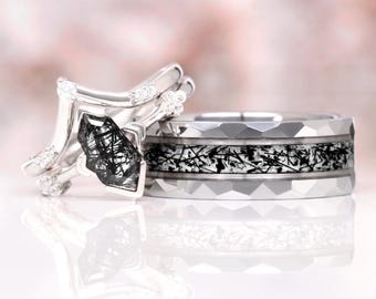 May include: A set of wedding bands featuring a silver band with a black and white stone and a silver band with a black and white inlay.