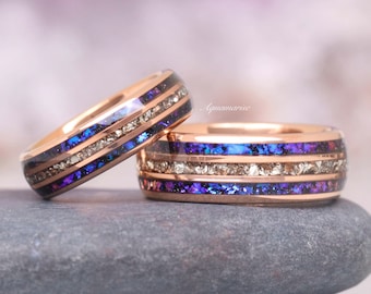Puede incluir: Dos alianzas de oro rosa con incrustaciones de color púrpura y oro. Las alianzas están apiladas una encima de la otra.