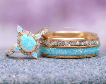 May include: Two gold rings with opalescent blue and white stones. One ring features a teardrop-shaped opal surrounded by small diamonds. The other ring has a band of blue opal, a band of clear stones, and a gold band.