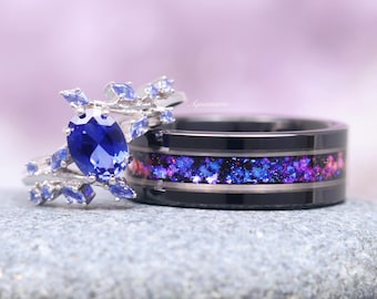 May include: A pair of wedding bands. The woman's ring features a large blue sapphire surrounded by smaller blue stones set in a silver band. The man's ring is a black band with a thin silver band and a purple and blue glitter inlay.