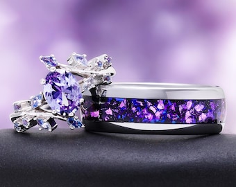 Puede incluir: Un conjunto de anillos en tono plateado que incluye una banda con una incrustación central de material iridiscente triturado en tonos morados y azules, y un anillo con una gran piedra ovalada morada rodeada de piedras claras y moradas.