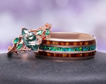 May include: Two rings, one with a rose gold band and a marquise-cut green stone with leaf accents and smaller green stones. The other ring has a rose gold band with a wood grain and green stone inlay.