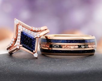 May include: A rose gold ring set featuring a unique design. One ring has a geometric shape with a dark blue center and small white stones. The other ring is a band with a dark blue and copper-colored inlay.