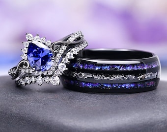 May include: A set of two rings. One ring features a large, blue, pear-shaped gemstone surrounded by smaller white stones. The other ring is black with bands of blue and silver inlay. The rings are displayed on a gray surface.