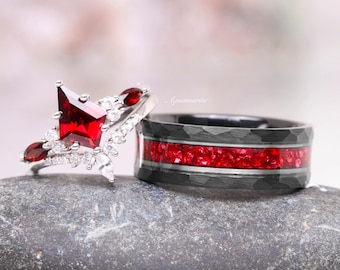 May include: A set of wedding bands featuring a silver ring with a large red gemstone and a black band with a red stone inlay.