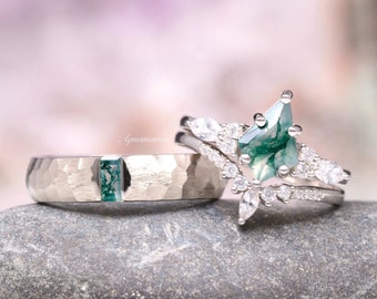 May include: A silver-toned ring set featuring a hammered band with a rectangular moss agate inlay and a matching engagement ring with a kite-shaped moss agate center stone surrounded by marquise and round white accent stones, with Aquamarise text.