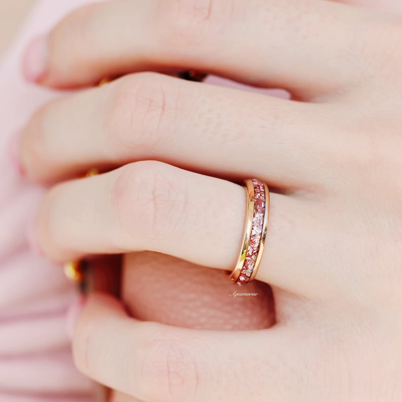 K&ouml;nnte beinhalten: Ein Ring aus Ros&eacute;gold mit einer Reihe kleiner rosa Steine.