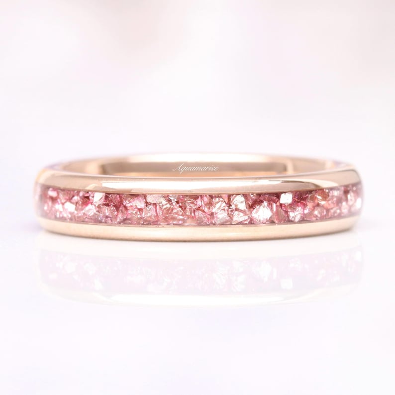 K&ouml;nnte beinhalten: Ein Ros&eacute;gold-Bandring mit einem d&uuml;nnen Band aus rosa zerkleinerten Diamanten.