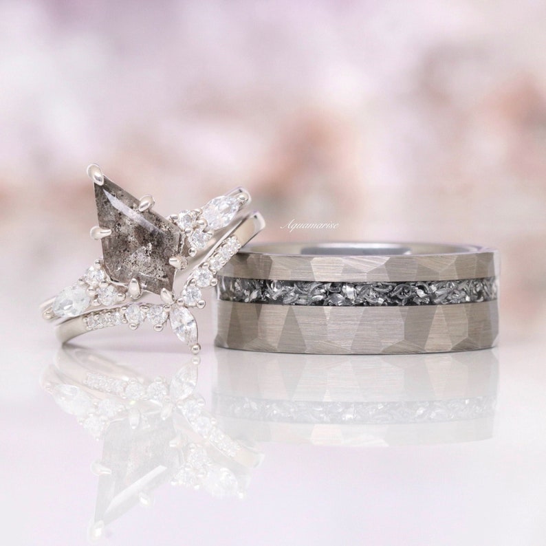 Pu&ograve; includere: Un set di anelli color argento composto da un anello di fidanzamento con diamante sale e pepe a forma di aquilone, pietre laterali taglio marquise e una fascia larga martellata con intarsio centrale di frammenti minerali, marchiato Aquamarise.