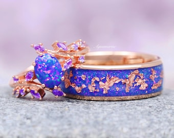 Puede incluir: Un conjunto de dos anillos de oro rosa con una piedra preciosa de ópalo púrpura y una banda con un diseño azul y dorado.