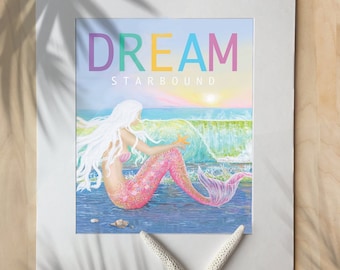 May include: A colorful print with the word "DREAM" in rainbow letters and the word "STARBOUND" below. The print features a mermaid with pink scales sitting on a rock in the ocean with a starfish in her hand. The ocean is blue and green with a sunset in the background.