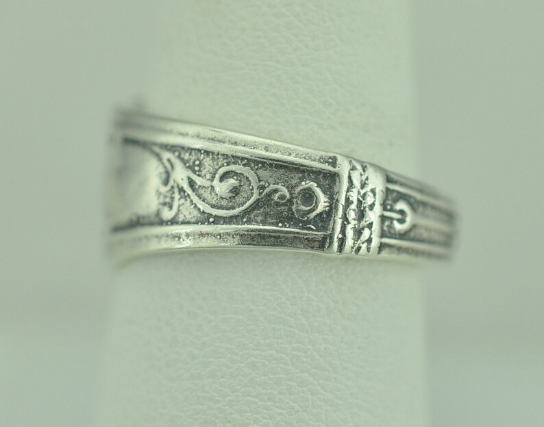 May include: Silver ring with a decorative floral design. The ring is made of sterling silver and has a polished finish.