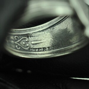 May include: Close-up of a silver ring with an inscription that reads "STERLING".
