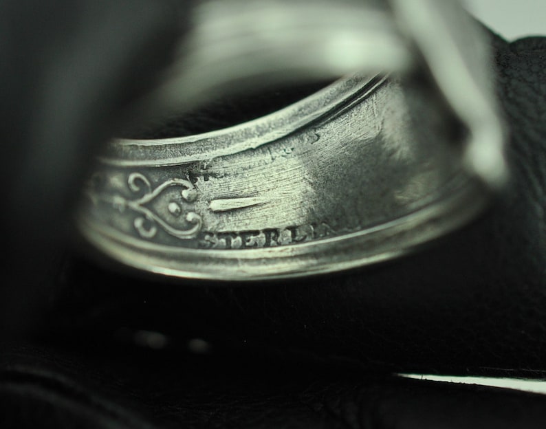 May include: Close-up of a silver ring with an inscription that reads "STERLING".