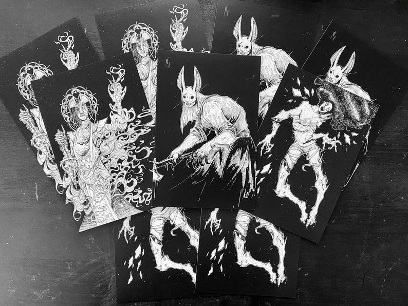 May include: A collection of rectangular art prints featuring high-contrast black and white ink illustrations. The designs depict various figures, including a rabbit-masked character holding an axe, a floating wrapped entity, and a robed figure.