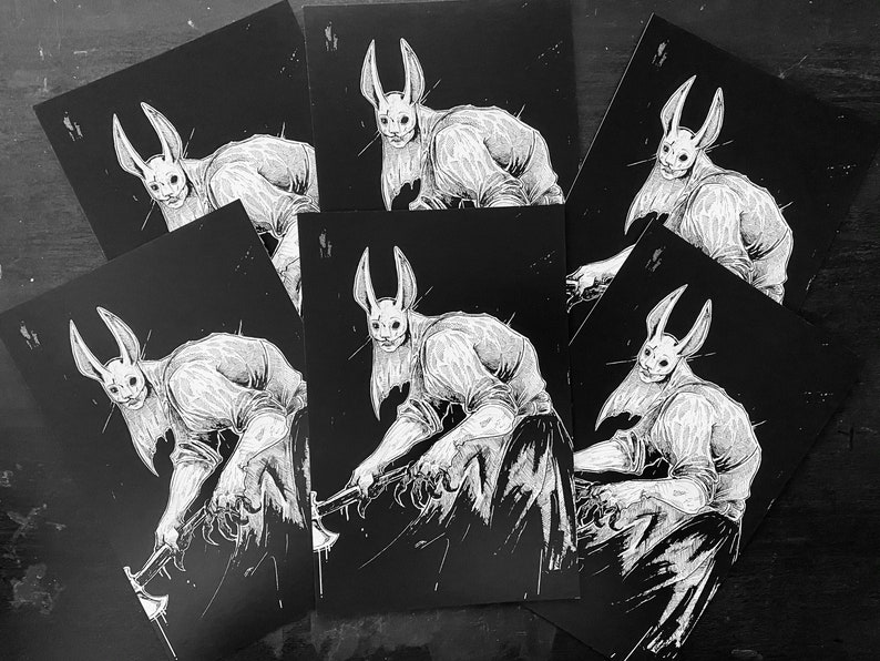 May include: A collection of rectangular art prints featuring a black and white illustration of a humanoid figure with long rabbit ears and a mask, wearing a shirt and pants, holding an axe with both hands in a dynamic, forward-leaning pose.