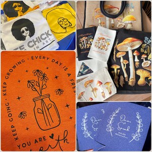 May include: A collection of tote bags, t-shirts and coasters featuring various designs. One tote bag has a black background with a mushroom illustration. One t-shirt has an orange background with a jar of flowers and the text "Keep going, keep growing, every day is a fresh start, you are worth it". Another t-shirt has a white background with the text "Free Chick in Art". One coaster has a blue background with white text that reads "Oscar & Sarah 08.08.2024".