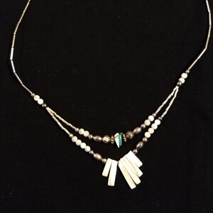 May include: A silver chain necklace with white and turquoise beads and a pendant of white shell pieces.