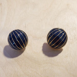 May include: A pair of gold and blue striped ball shaped earrings.