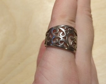 May include: A silver filigree ring with a wide band and intricate floral design.