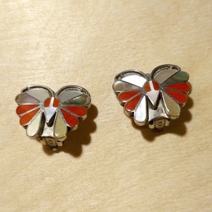 May include: A pair of butterfly-shaped earrings with a multi-colored inlay of red, white, and gray stones.