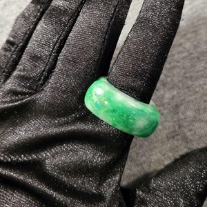 May include: A smooth, polished ring featuring a vibrant green and white marbled pattern. The band has a rounded, thick profile with a glossy finish, displaying variations of emerald and lime green hues blended with opaque white streaks throughout.