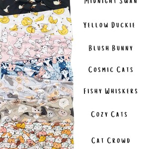 May include: A stack of seven fabric headbands with various patterns. Designs include swans, ducks, bunnies, cats, and fish. Text on the right reads "Midnight Swan", "Yellow Duckie", "Blush Bunny", "Cosmic Cats", "Fishy Whiskers", "Cozy Cats", and "Cat Crowd".