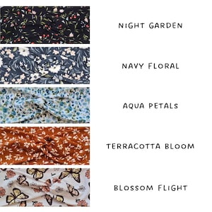 May include: A selection of fabric headbands with floral and butterfly designs. The headbands are labelled Night Garden, Navy Floral, Aqua Petals, Terracotta Bloom, and Blossom Flight. Each headband has a twisted knot.