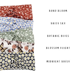 May include: Five knotted headbands with various patterns: Boho Bloom in rust with white florals, Daisy Sky in light blue with white daisies, Botanic Bliss in sage green with white florals, Blossom Flight with butterflies, and Midnight Daisy in black.