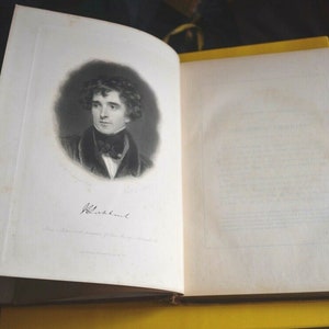 May include: An open antique book with a portrait of a man in a dark coat and cravat. The portrait is a black and white lithograph with the name "Blackburne" below. The book's pages are off-white, and the binding is visible.