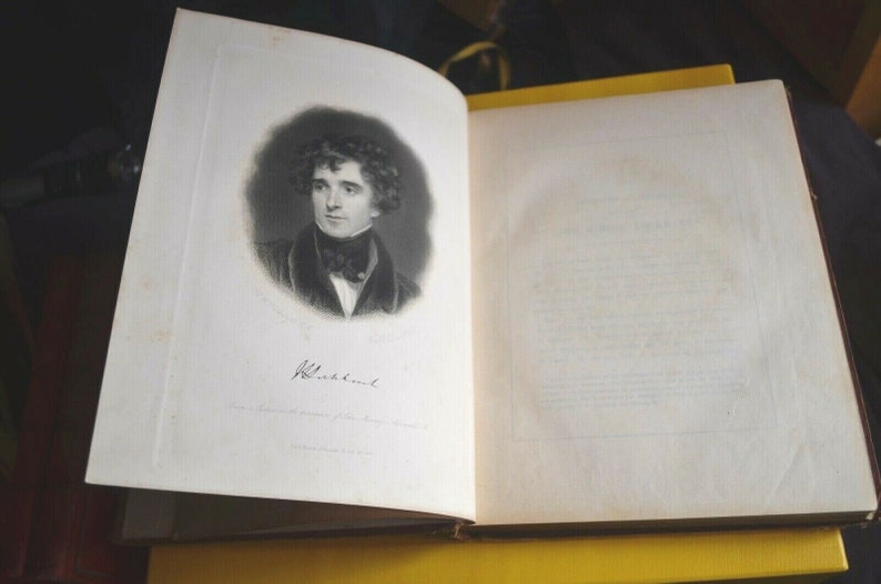 May include: An open antique book with a portrait of a man in a dark coat and cravat. The portrait is a black and white lithograph with the name "Blackburne" below. The book's pages are off-white, and the binding is visible.