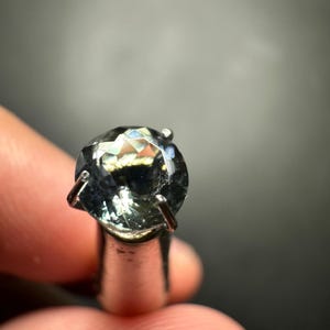 May include: A round, faceted, light blue gemstone with a silver setting.