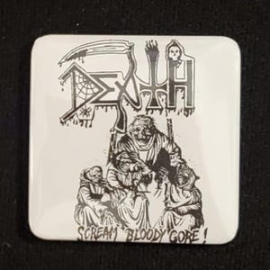 May include: Square white button with a black and white illustration. The image features the word "DEATH" in a stylized font, a grim reaper, and figures in robes. The text "SCREAM BLOODY GORE!" is at the bottom.
