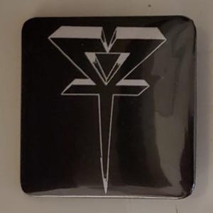 May include: Square black button with a white geometric design. The design features a stylized V shape at the top, a triangle in the middle, and a vertical line extending downwards. The button has rounded corners.