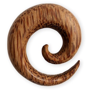 May include: A spiral-shaped wooden ear gauge with a brown and reddish-brown wood grain pattern.