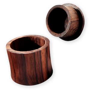 May include: A wooden box with a lid, crafted from dark wood with a natural grain pattern. The box is cylindrical and has a smooth, polished finish.