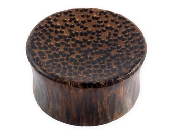 Op de afbeelding: Een bruine houten oorplug met een zwart en bruin patroon.