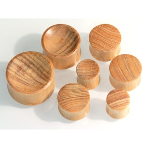 May include: A set of seven wooden ear gauges in various sizes. The gauges are made from natural wood and have a smooth, polished finish.