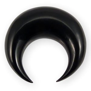 May include: A smooth, solid black crescent-shaped body jewelry piece. This curved, tapered item features a polished, glossy finish and pointed ends, forming a distinct moon-like silhouette. The object is uniform in color and texture throughout.