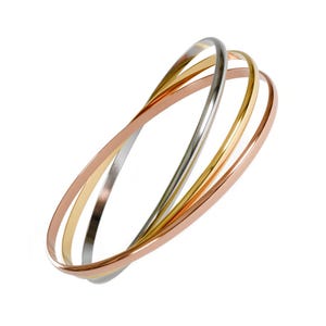 Peut inclure: Un bracelet jonc triple composé de trois anneaux métalliques fins entrelacés aux tons argent, or jaune et or rose. Les surfaces lisses et polies des anneaux circulaires créent un design continu et superposé avec une finition réfléchissante.