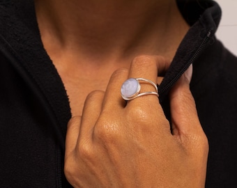 May include: A silver ring with a light purple gemstone set in a bezel setting. The ring has a double band design.